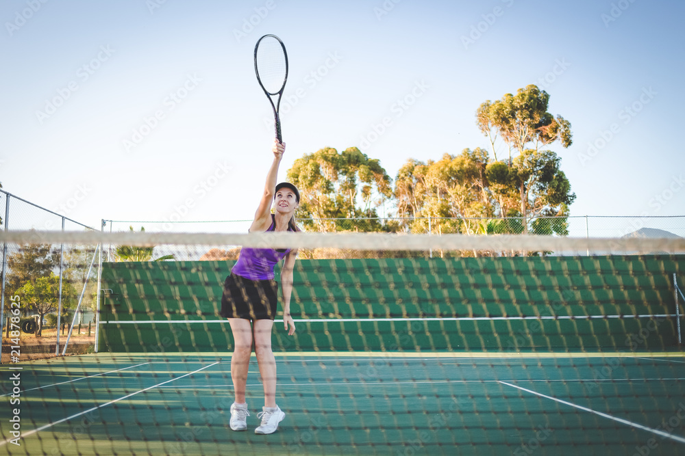 Close up image of a female tennis player playing tennis on a court in bright sunlight
