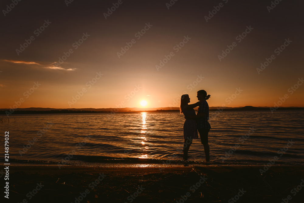 guy and girl hugging the sea at sunset