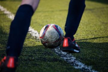 Football soccer player ready to kick the football ball, in green field on a sunny day.