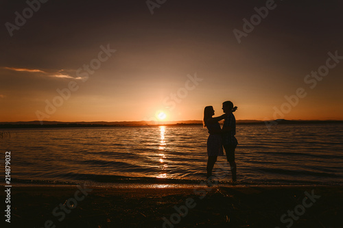 guy and girl hugging the sea at sunset