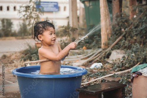 Children play and bathed water in the garden,sitting in a bucket of water. Concept of raising children.