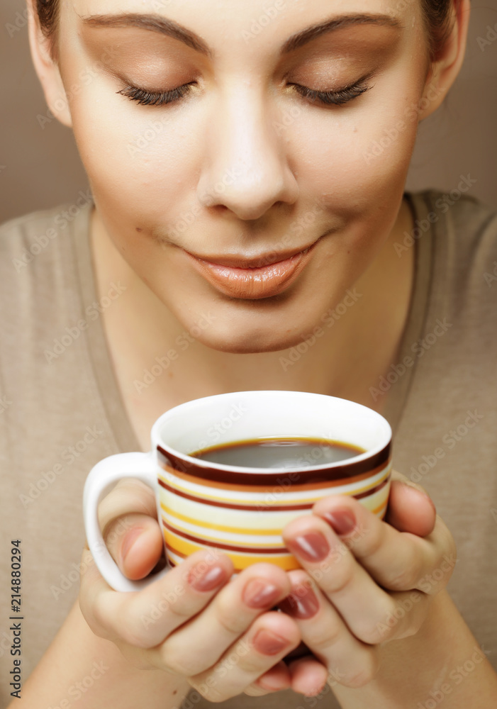portrait of a beautiful woman with a cup of coffee standing on the beige background portrait of a beautiful woman with a cup of coffee standing on the beige background