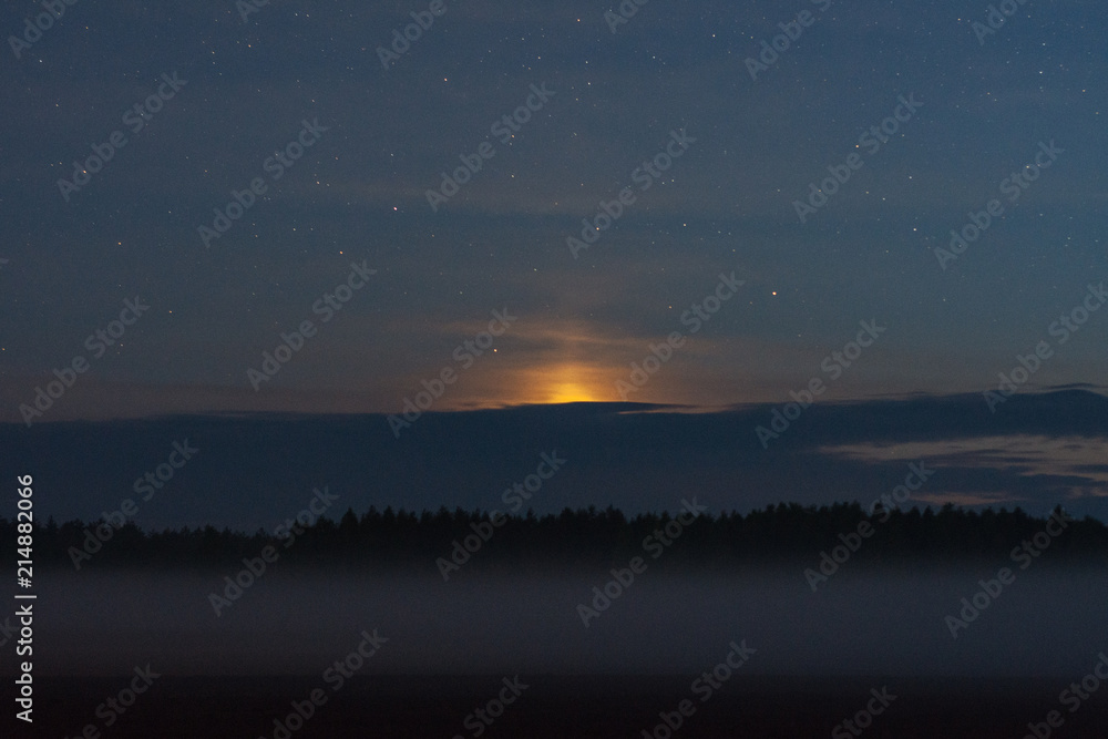 Sunset of the moon over the forest and fog