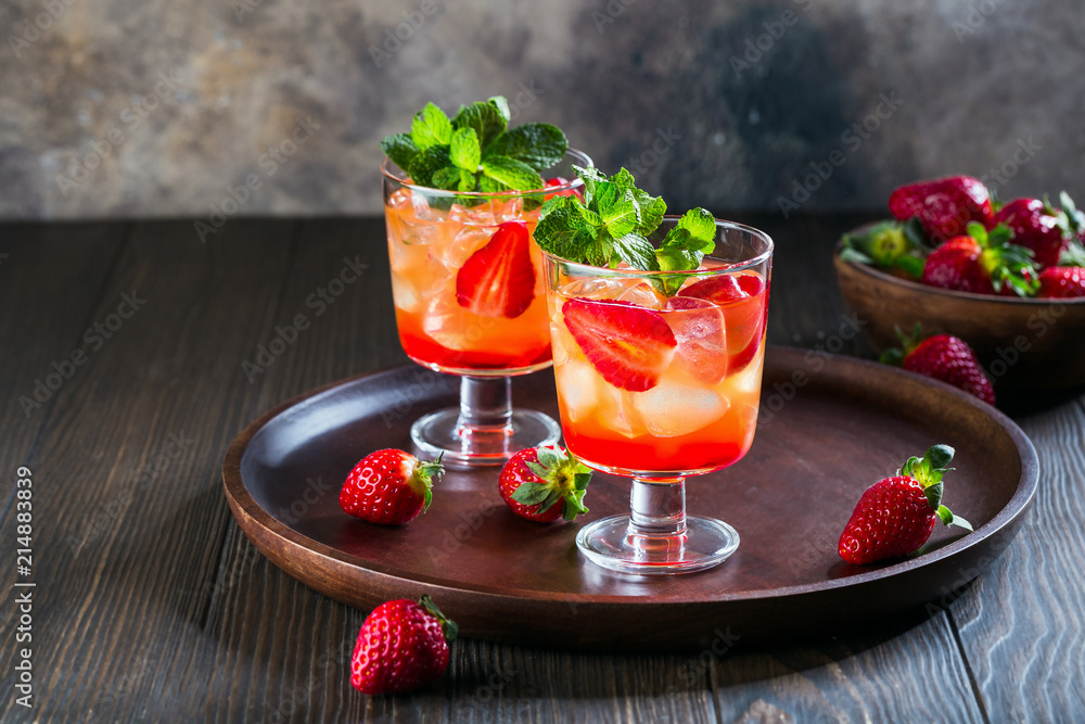Red cocktail with ice, mint leaves and strawberry on wooden background. Red cocktail with ice, mint leaves and strawberry on wooden background.