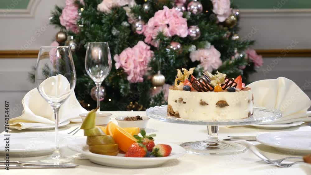 Restaurant concept. New Year and Merry Christmas feast table. Waiter in gloves opens and then closes glass dish with a fruit cake Restaurant concept. New Year and Merry Christmas feast table. Waiter in gloves opens and then closes glass dish with a fruit cake