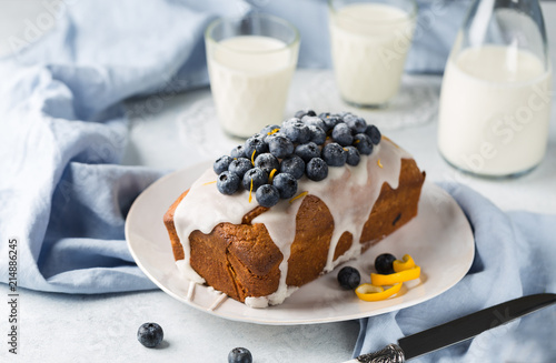 Healthy Blueberry Loaf Cake on white plateTopped with Icing Sugar Glaze and Fresh Berries. 