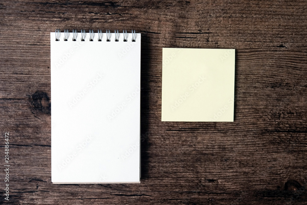 Top view image of blank notebook and empty sticky note paper on the wooden table.. Top view image of blank notebook and empty sticky note paper on the wooden table..