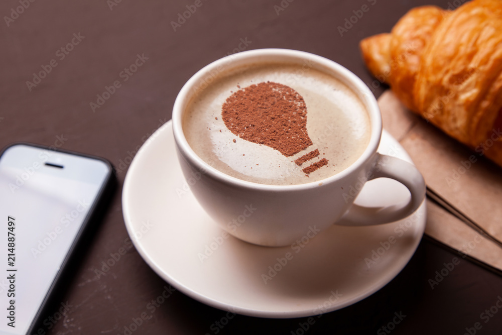 Cup of coffee with the idea of a light bulb on the foam. Coffee gives new ideas and creativity. Morning coffee Cup of coffee with the idea of a light bulb on the foam. Coffee gives new ideas and creativity. Morning coffee