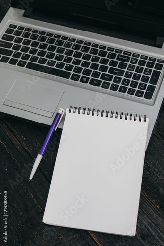 the laptop and a blank notebook or Notepad on the table