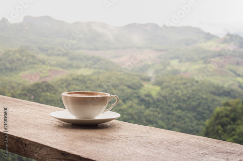 A cup of coffee on the table and a beautiful mountain background.