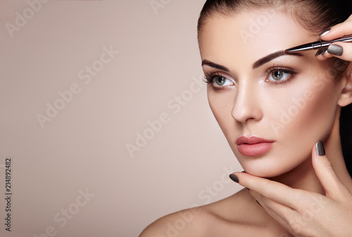Beautiful Brunette Woman Paints the Eyebrows. Beautiful Woman Face. Makeup Detail. Beauty Girl with Perfect Skin photo