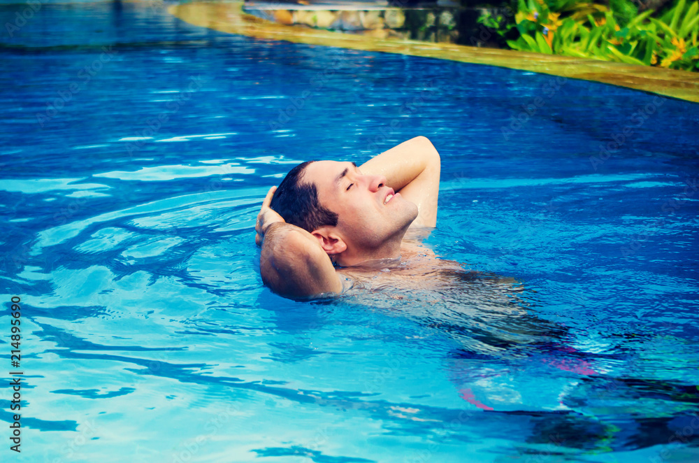 Perfect morning at villa. Man relishing warm water and silence in a swimming pool