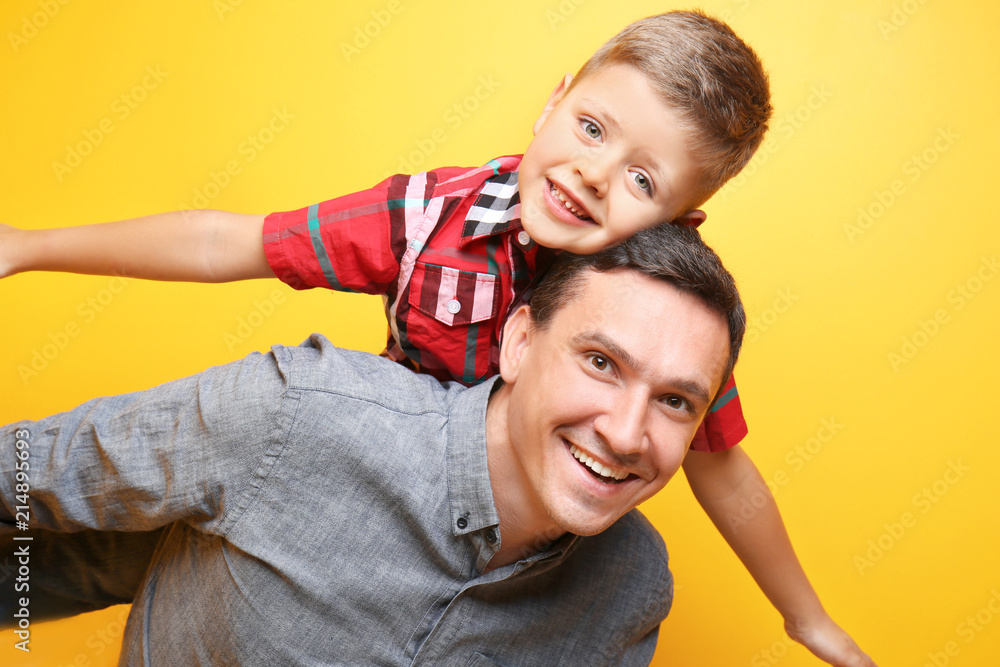 Fototapeta premium Little boy and his dad playing on color background
