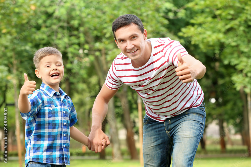 Little boy and his father showing thumb-up gesture outdoors Little boy and his father showing thumb-up gesture outdoors