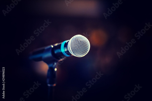 Cool mic on a stand in front of the concert hall, beautiful blurred dark background with a copy space for a message.