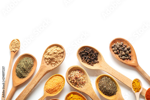 Wooden spoons with different spices on white background