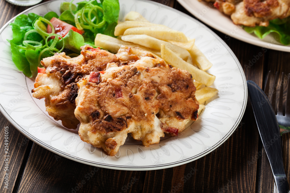 Chicken medallions with red peppers served with chips Chicken medallions with red peppers served with chips