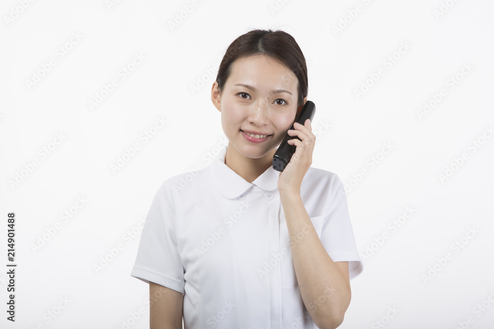 電話の受話器を持って微笑む白衣を着た女性 電話の受話器を持って微笑む白衣を着た女性