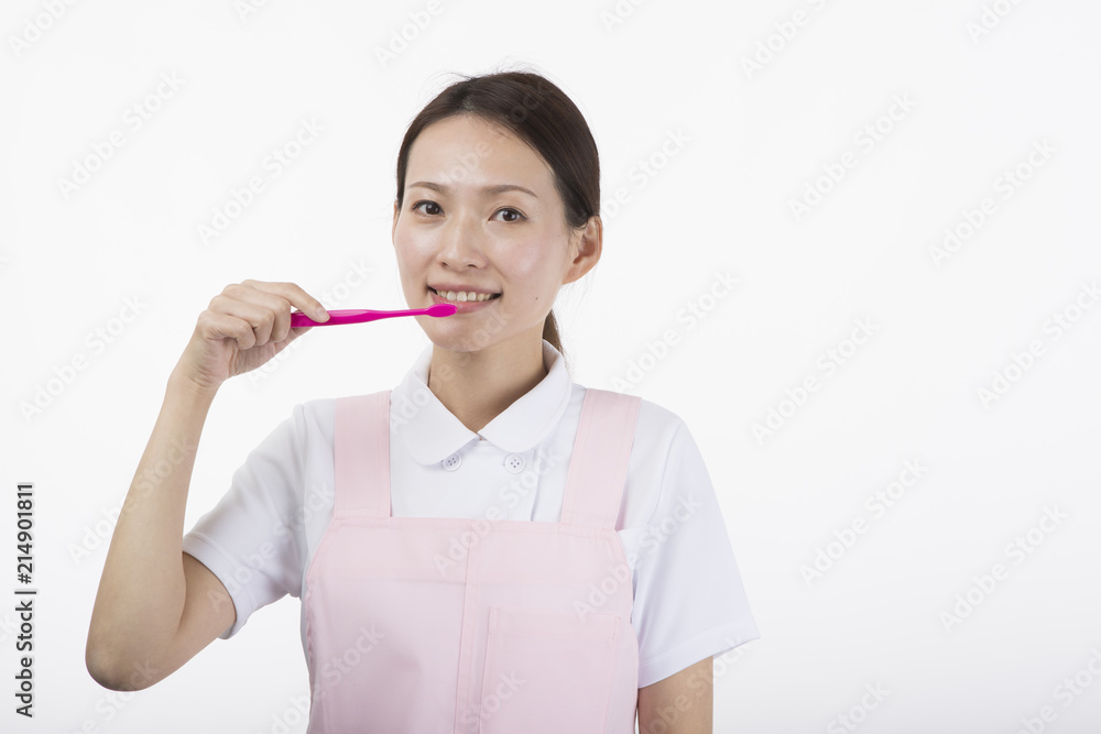 歯ブラシを持って微笑む白衣とピンクのエプロンを着た女性 歯ブラシを持って微笑む白衣とピンクのエプロンを着た女性