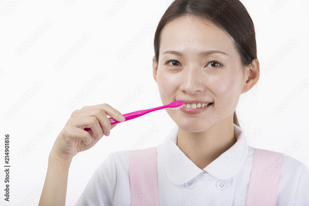 歯ブラシを持って微笑む白衣とピンクのエプロンを着た女性 歯ブラシを持って微笑む白衣とピンクのエプロンを着た女性