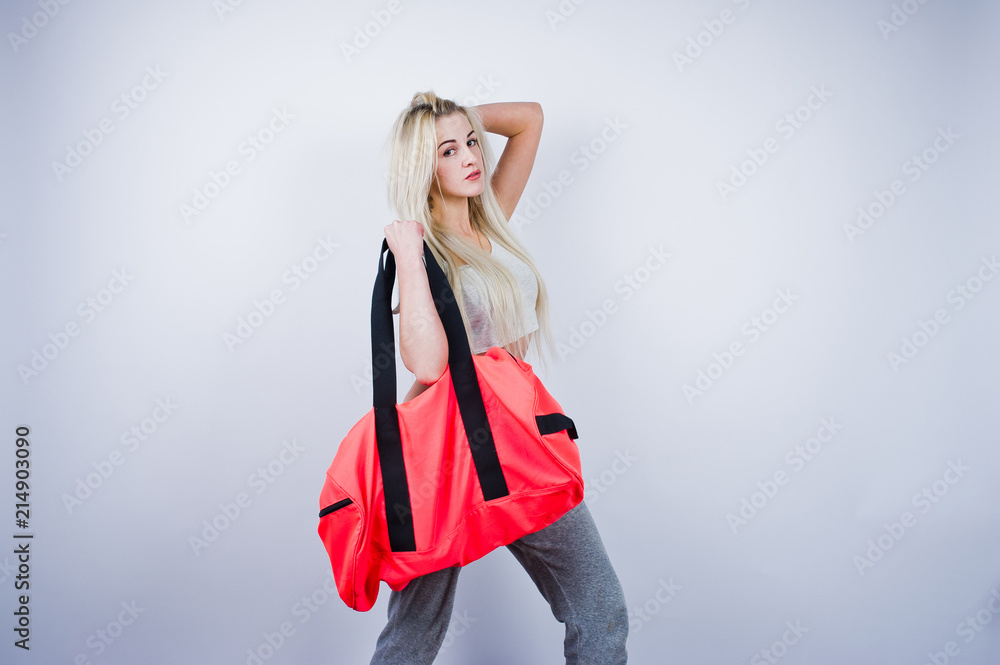 Blonde sporty girl with big sport bag posed at studio against white background.