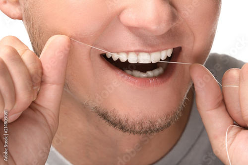 Man flossing his teeth on white background, closeup © Pixel-Shot