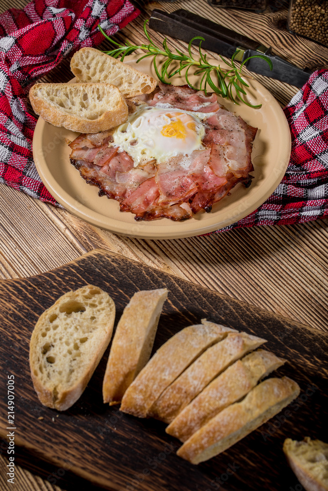 Plate of breakfast with fried eggs, bacon and bread.