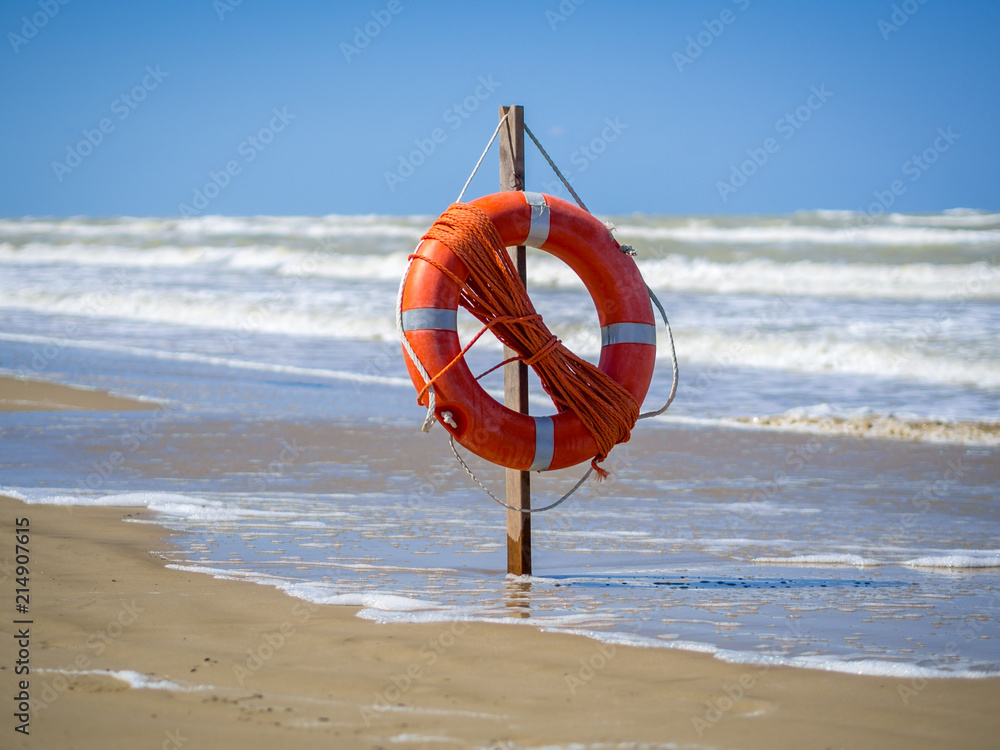 Lifebuoy with rope on the beach. Used as safety equipment helping sea lifeguards to rescue the people.