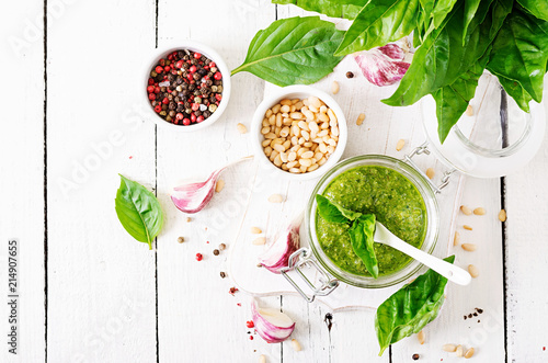 Homemade pesto sauce fresh basil, pine nuts and garlic on white wooden background. Italian food. Top view. Flat lay.