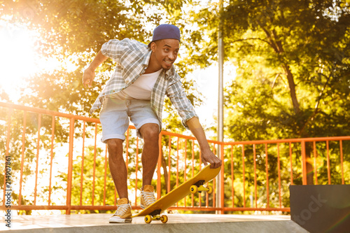 Happy young african man with skateboard riding