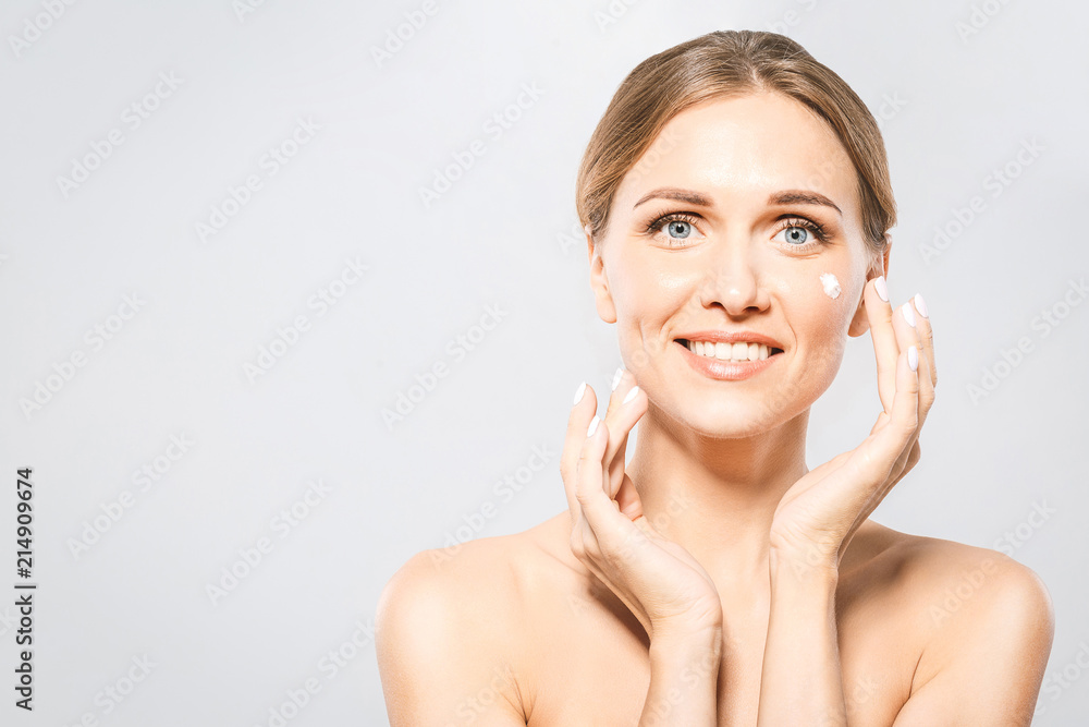 Portrait of young beautiful woman smiling while taking some facial cream isolated on white background with copy space. Portrait of young beautiful woman smiling while taking some facial cream isolated on white background with copy space.