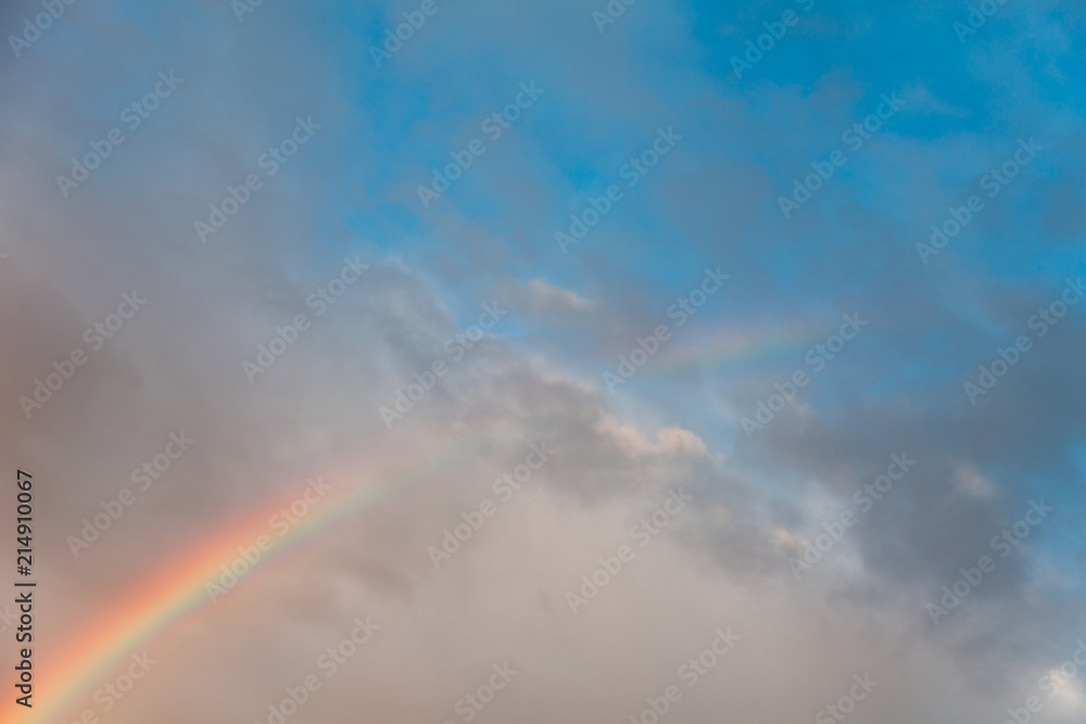Rainbow is on blue sky with clouds at sunset. Beautiful sky background and texture.