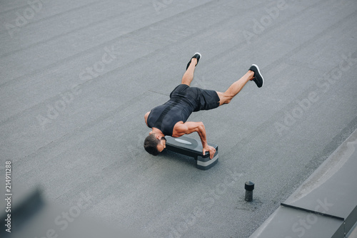 Fototapeta Naklejka Na Ścianę i Meble -  high angle view of sportsman training with step platform and standing on hands on roof