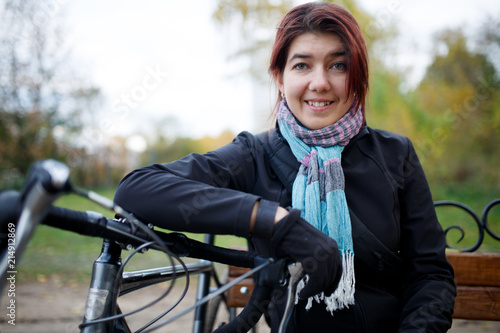 Image of smiling woman sitting on bench next to bicycle