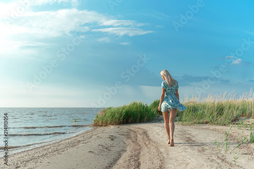 a girl in a blue dress strolls along the seashore © Mikhaylovskiy 