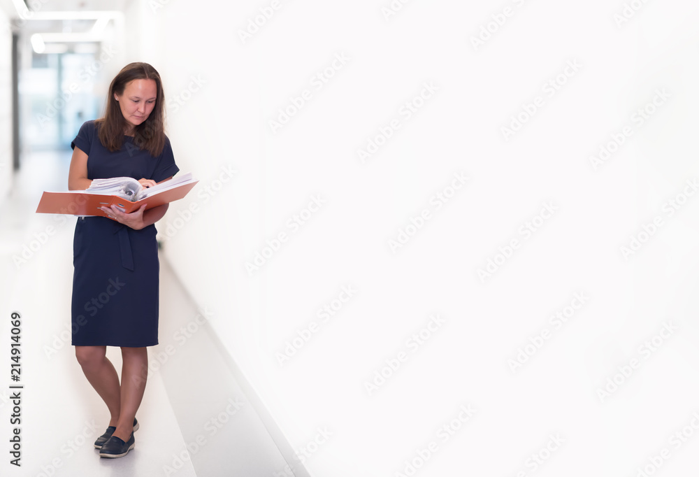 Portrait of confident beautiful middle age business woman holding orange folder in her hands standing on light background. Copyspace Portrait of confident beautiful middle age business woman holding orange folder in her hands standing on light background. Copyspace