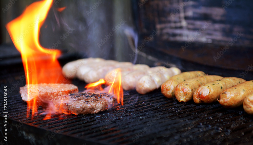 Flame rises around a hamburger on a barbecue Flame rises around a hamburger on a barbecue