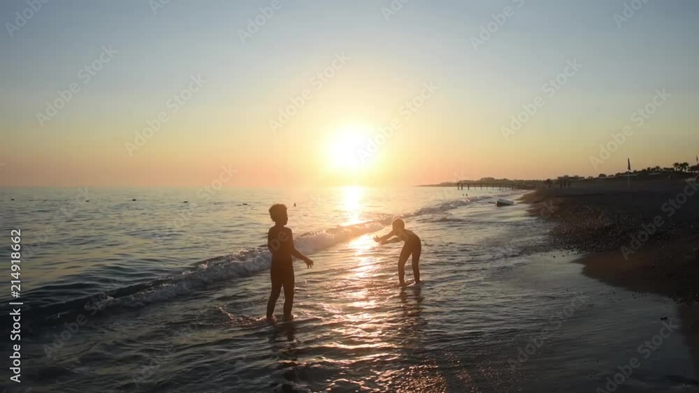 two cool boys playing on the sea on the sunset. Brothers put water on each other on the sunset. Cool childhood. Best friends. two cool boys playing on the sea on the sunset. Brothers put water on each other on the sunset. Cool childhood. Best friends.