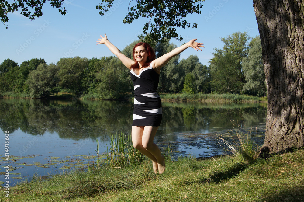 young woman jumping for joy at a lakeside young woman jumping for joy at a lakeside