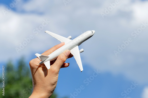 Airplane model in hand on sunny sky. Concepts of travel, transportation