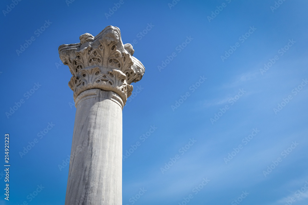 Ancient antique Greek column against the blue sky, look up, copy space