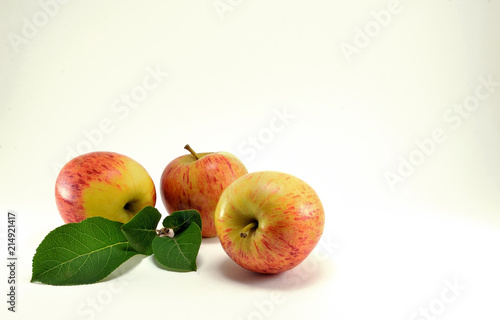 Three ripe red apples and a green twig.