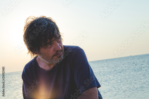 Handsome man with a faraway look / Portrait of good looking middle aged man on the beach while sunsets