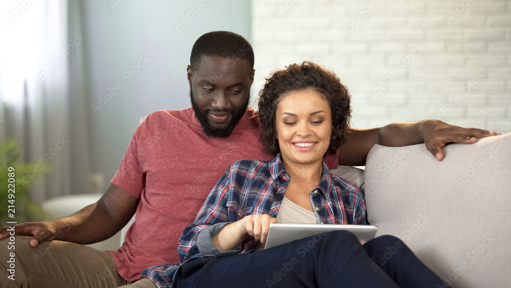 Multiracial couple booking tickets and hotel on tablet, planning vacation online Multiracial couple booking tickets and hotel on tablet, planning vacation online