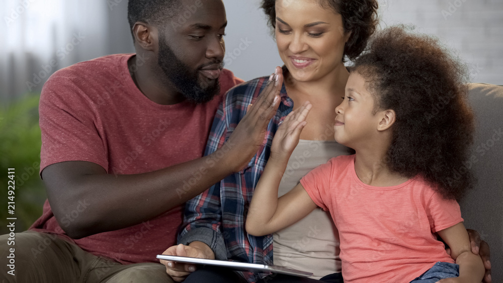 Black daddy giving high five to little curly-haired daughter, family together Black daddy giving high five to little curly-haired daughter, family together