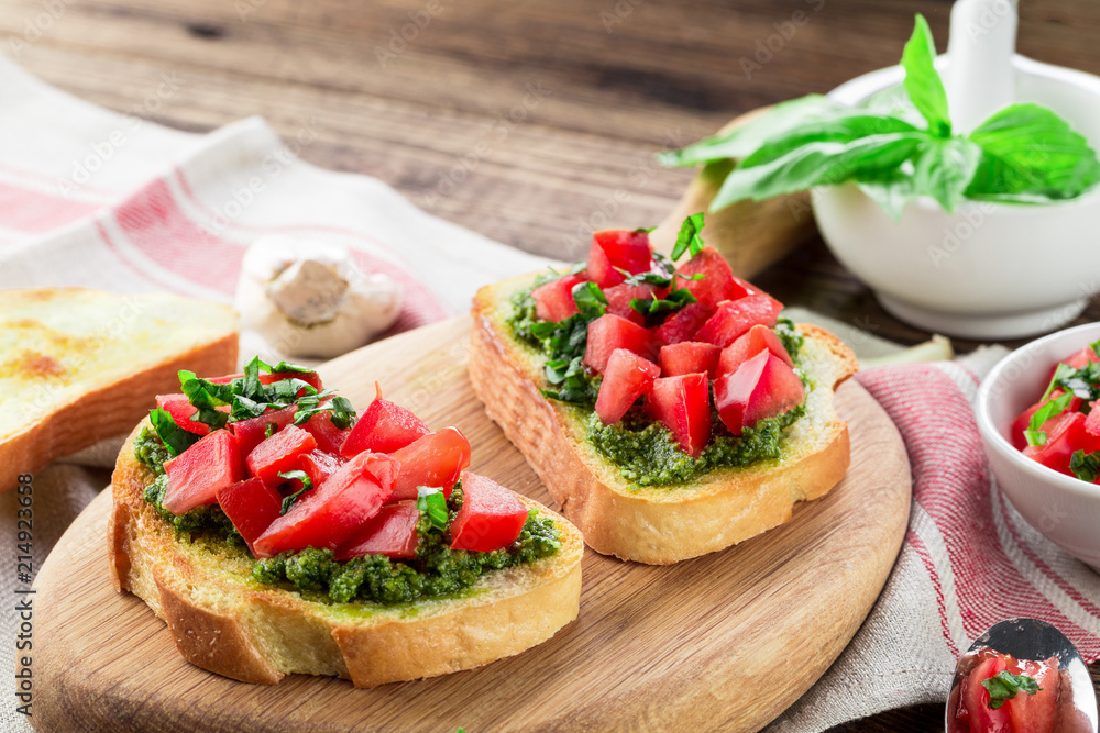 Bruschetta with fresh pesto, basil leaves and tomatoes. Wooden background