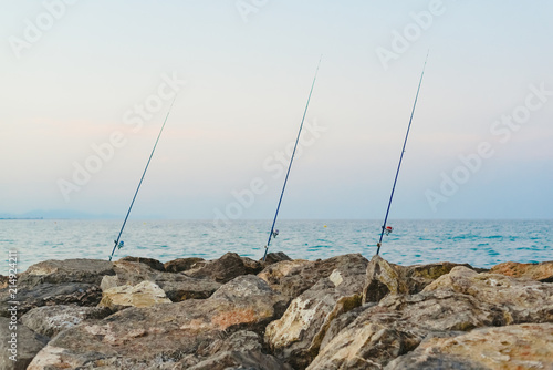 Fishing rods fixed to the rocks near the sea coast without fishermen