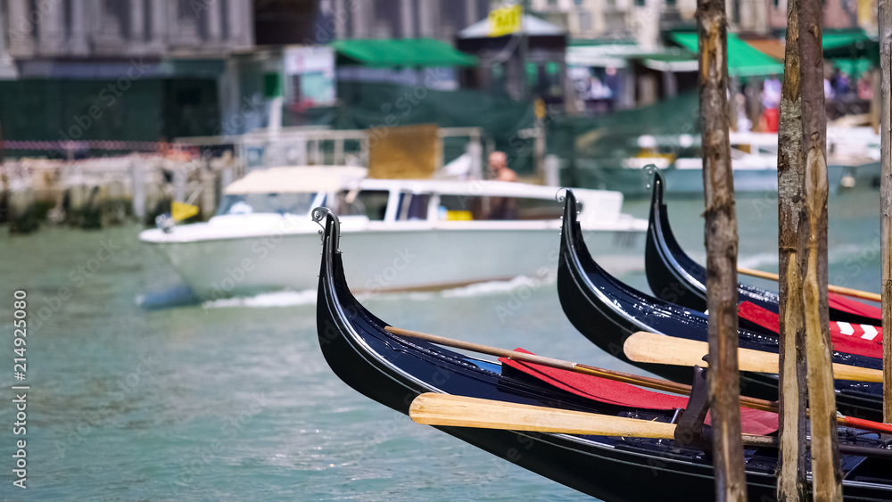 Water taxi carrying tourists in Venice, gondolas parked along canal, sightseeing