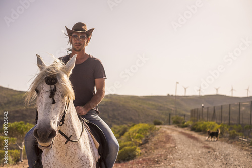 modern man cowboy enjoy a natural and alternative lifestyle riding a white horse. friendship and nature outdoor for beautiful people living a different life in the rural country side