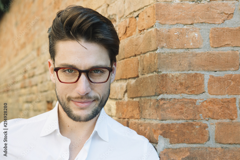 Portrait of a smiling man wearing glasses at brick wall Portrait of a smiling man wearing glasses at brick wall
